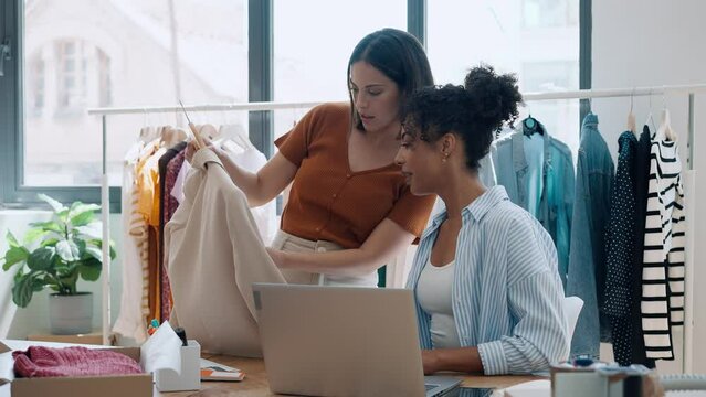 Video of two fashion designers working with laptop and deciding details of clothes new collection in the sewing workshop.