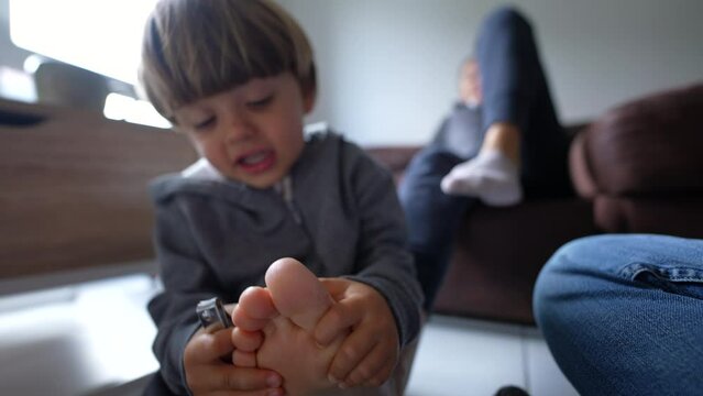 Playful Child and Mother's Pedicure Time at Home, little boy attempts to trim reluctant parent, closeup toes and feet while kid holds for trimming, fun lifestyle moment