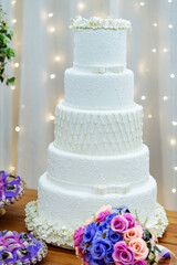 a table decorated with sweets and flowers pink, purple and a white wedding cake