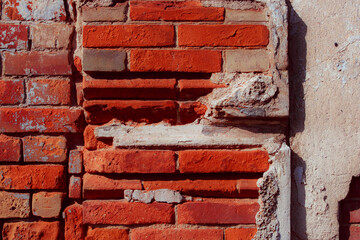 Old grungy red brick wall. Free space for an inscription. Can be used as a background or poster. Fragment of a wall with bumps and peeling paint.