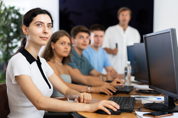 During lesson on computer technology and programming, boys and girls students sit at workplaces,...