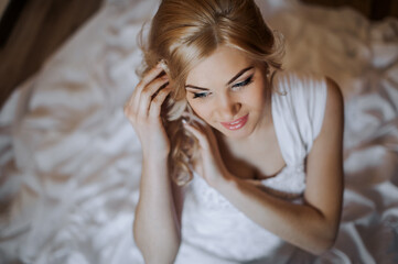 Fototapeta premium Wedding photography, close-up portrait, top view of a beautiful happy smiling blonde bride in a white lace dress.
