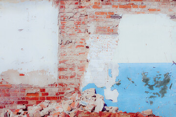 White and blue plaster on a dilapidated brick wall. Preparing the wall for repairs. Can be used as a background or poster. Fragment of a wall with bumps and peeling paint.