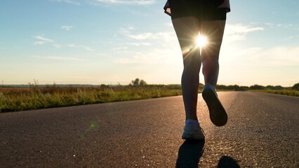 silhouette sports girl running along road sunset, legs close-up, triathlon, ready marathon, sports...