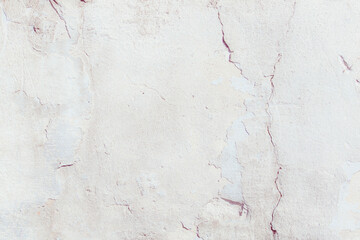 White plaster wall with deep scratches and chips. Various variations of abrasions. Can be used as a background or poster. Fragment of a wall with bumps and peeling paint.