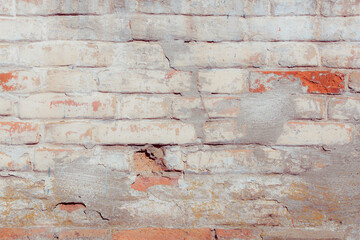 The wall is made of red brick locally painted white. Covered with white plaster. Free space for an inscription. Can be used as a background or poster. Fragment of a wall with bumps and peeling paint.