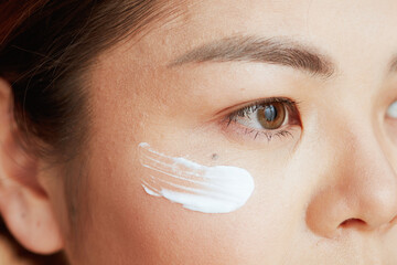 Closeup on asian woman with eye cream on face