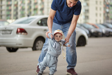 the first steps of the child are held by the father's hands.