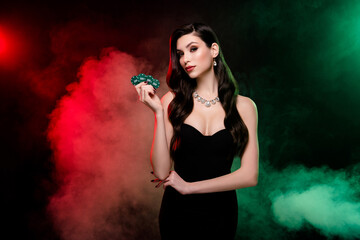 Photo of classy lady croupier in private vip poker club show chips for another game over mist neon...