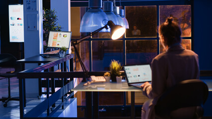 Entrepreneur checking financial report on computer, working afterhours on economy diagrams statistics. Office worker planning business growth and profit investment in corporate space.