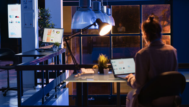 Entrepreneur checking financial report on computer, working afterhours on economy diagrams statistics. Office worker planning business growth and profit investment in corporate space.