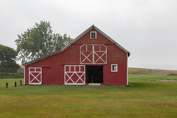 A Red Barn on a Green Meadow, Homestead in South Dakota on a Rainy, Stormy Autumn Day - 694569525