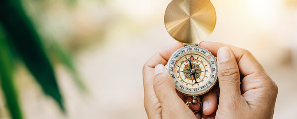 In a close-up shot a woman uses a compass in the forest. Her hand holds the compass representing...