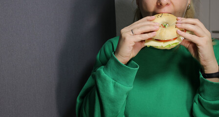 Close up of woman eating a vegetarian bagel with cheese and vegetables