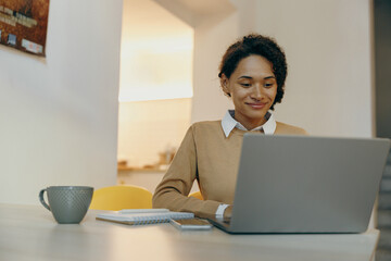 Smiling business woman working remotely on laptop from home. Distance work concept 