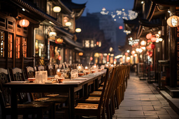 Empty outdoor dining area lined with wooden chairs and tables, illuminated by warm lantern lights...