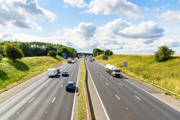 Traffic on a three-lane motorway through the English countryside on a sunny summer day