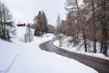 Empty winding road in a snowy mountain landscape on a cloudy winter day