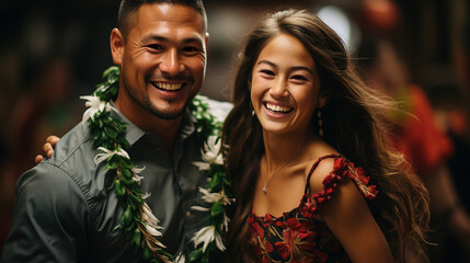 Cheerful couple in traditional Hawaiian attire with lei necklaces, sharing a joyful embrace at an outdoor festive event.