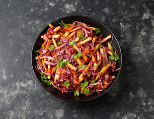 Red Cabbage salad with apples and carrots in black bowl
