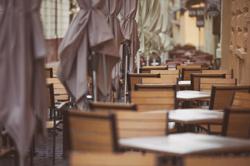 Umbrellas and tables of the bar. Coffeehouse cafe restaurant terrace. Wooden chairs and tables....