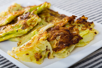 Leaves of cabbage fried in batter served on white plate..