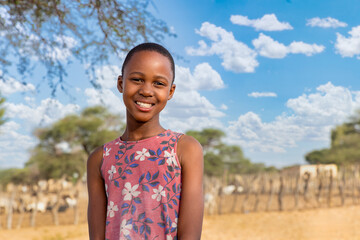 village , african girl at the farm, kraal with goats in the background, Kalahari small livestock