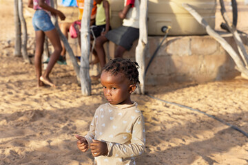 little african girl with braids playing with her mates near the water reservoir at the farm,...