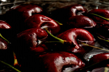 Cerezas maduras con ramita verde flotando en agua dentro de un plato