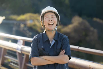 Fotobehang ヘルメットを持つ未来を見つめる中年女性の現場監督の正面、転職や採用のイメージ　半逆光 © kapinon