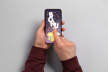 Bonus gaining. Man using smartphone on light grey background, top view. Illustration of open gift...