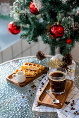 Cup of hot coffee and bakery goods Various waffles and breads are on the table. and decorated with Christmas There is a Christmas tree and various decorations. to celebrate the Christmas festival.