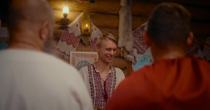 portrait of young Slavic man talking with guests in interior of ancient Ukrainian house, 4K, Prores