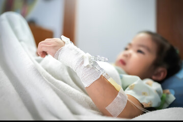 Little girl patient in hospital bed with saline intravenous (IV)