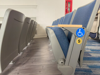 Close up image of empty ADA, accessible, gray and blue theater, auditorium seats, chairs.	