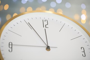 Clock showing five minutes until midnight on blurred background, closeup. New Year countdown
