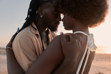 Black newlyweds hugging at sunset in nature