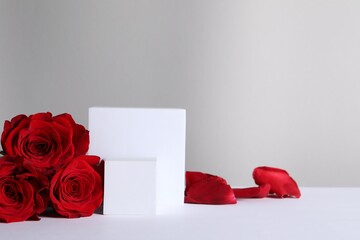 Stylish presentation for product. Cubes, beautiful roses and petals on light background, space for text