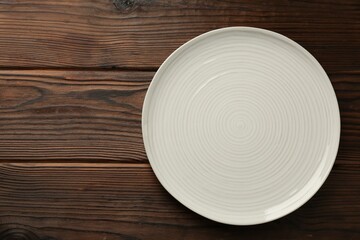 Beautiful ceramic plate on wooden table, top view. Space for text