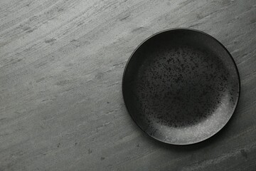 Beautiful ceramic plate on black table, top view. Space for text