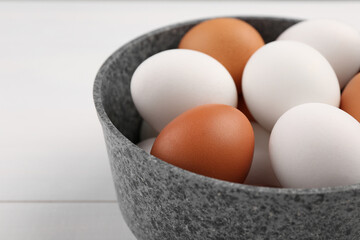 Unpeeled boiled eggs in saucepan on white table, closeup. Space for text