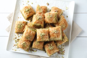 Delicious fresh baklava with chopped nuts on white wooden table, top view. Eastern sweets