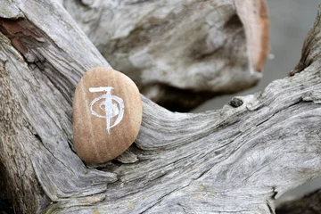 Photo sur Plexiglas Zen A close up image of a healing reiki symbol and white sage smudge stick on a weathered and worn piece of driftwood with an ocean background. 