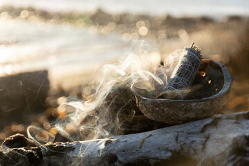 A close up image of a smoldering smudge kit in the golden glow of an evening sunset. 