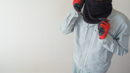 ネックウォーマーで防寒対策をする作業服の男性 - obrazy, fototapety, plakaty