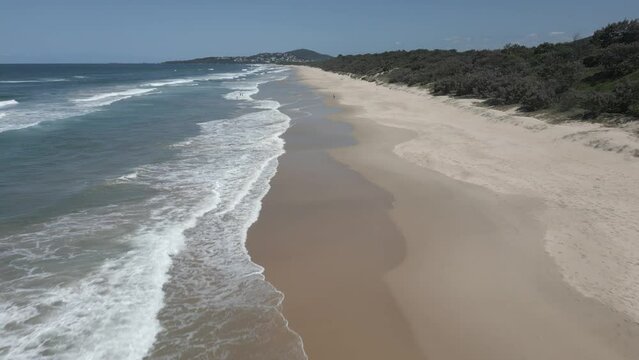 Aerial: Waves gently lap at sand beach of Warners Bay, NSW, Australia
