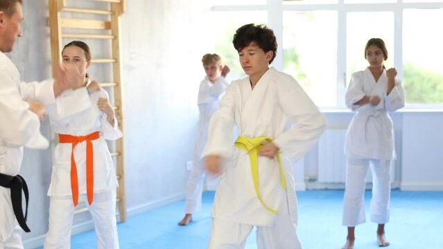 Children athletes starting position and studying and repeating sequence of punches and painful techniques in karate kata technique. Oriental martial arts, training and obtaining black belt