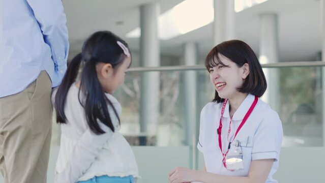 病院内にて話す笑顔の看護師と患者の子供
