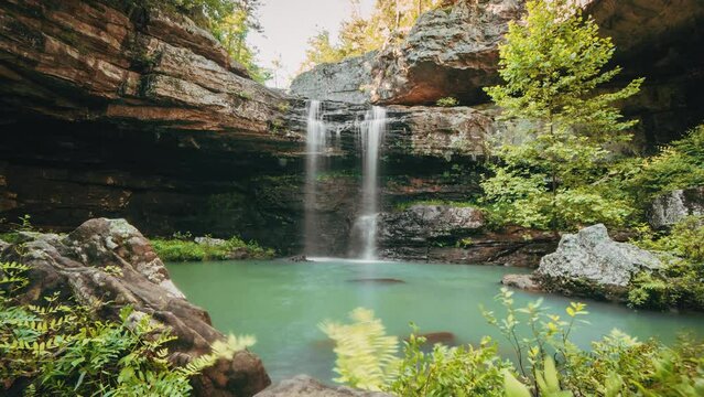 Time-lapse of people swimming in a secluded pool below a waterfall