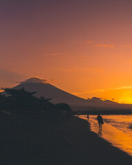 Red colour sunset, Agung volcano background. Beautiful sunset Amed beach. People are walking on the beach in the distance. Indonesia.
